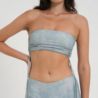 woman wearing minimalist blue green tankini top with rouched side seams and matching low rise swim shorts, sustainable swimwear to swim and surf in.