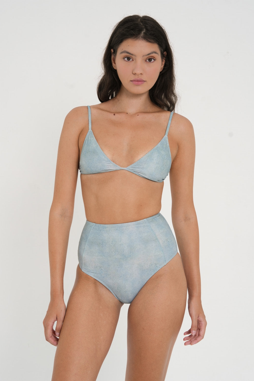 woman wearing fixed triangle bikini top in sea glass print, designed for both style and comfort. Crafted from 78% recycled nylon and 22% Lycra, offering a supportive and quick-drying fabric. Worn with matching high waisted sustainable swimwear bottoms.