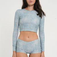 woman wearing blue green long sleeve cropped rashguard and matching low rise swim short, sustainable swimwear for surf and sun protection.