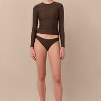 woman wearing brownlong sleeve minimalist rashguard sustainably made for sun protection and surfing.