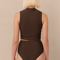 A high-waisted brown sustainable swimwear bikini bottom with minimalist design and moderate coverage, modelled by a woman in a matching bikini top.