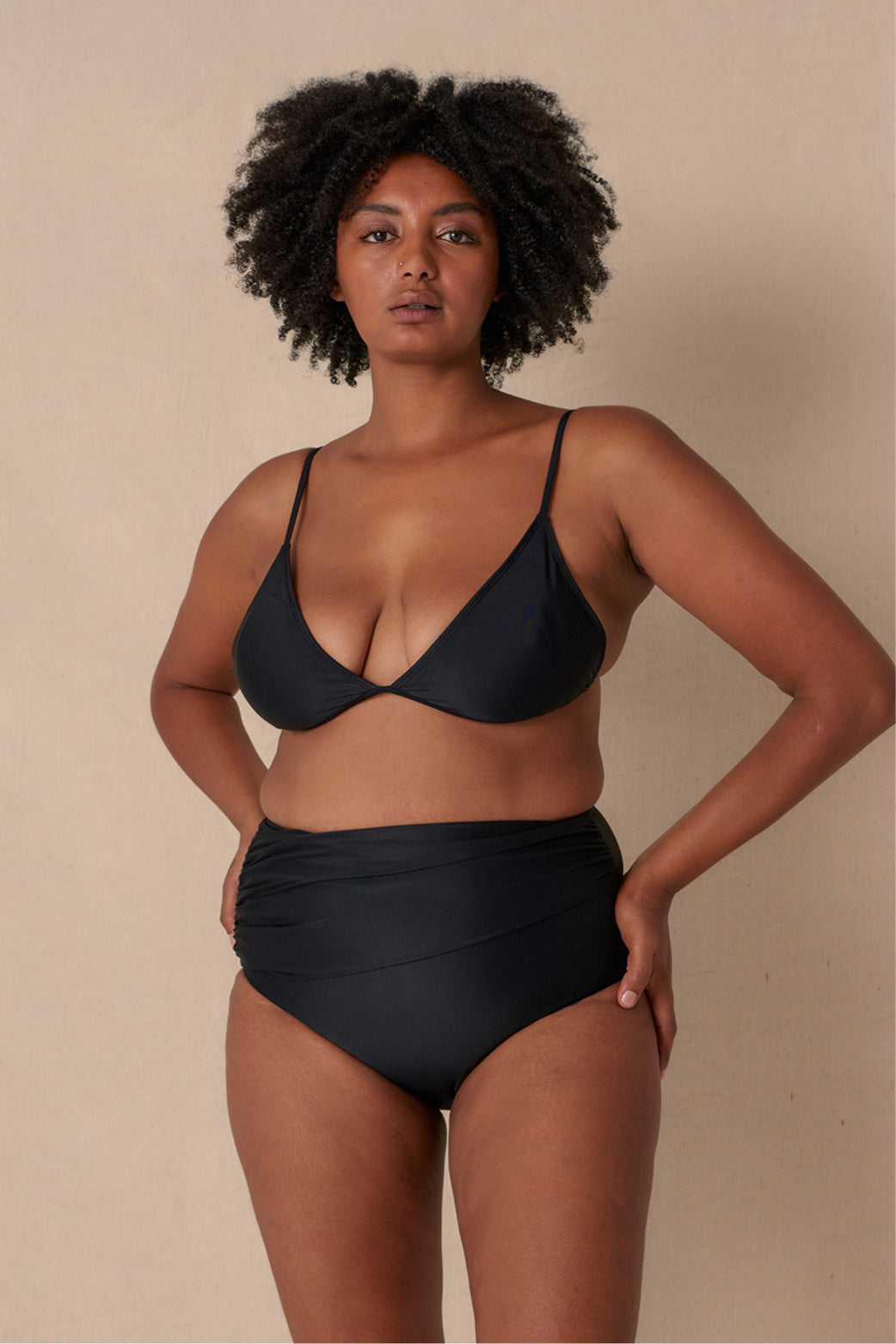 Woman wearing a black triangle bikini top with adjustable straps and removable cups, paired with matching bottoms made with sustainable swimwear fabrics.
