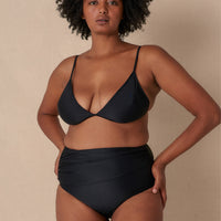 Woman wearing a black triangle bikini top with adjustable straps and removable cups, paired with matching bottoms made with sustainable swimwear fabrics.