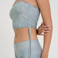 woman wearing minimalist blue green tankini top with rouched side seams and matching low rise swim shorts, sustainable swimwear to swim and surf in.